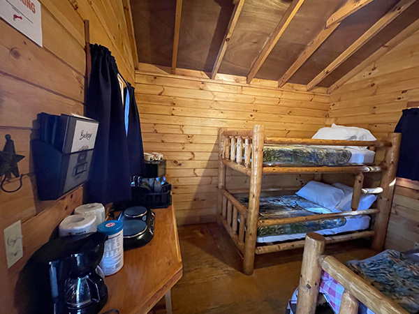inside cabin, desk on the left wall and bunk beds and a single bed to the right